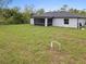 View of home's backyard including lush grass, large lot, screened-in porch, and the side of the home at 19185 Sherbrooke Ave, Port Charlotte, FL 33954