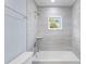 Well-lit bathtub with shower and window that offers a view of the outdoors and tiled shower walls at 19185 Sherbrooke Ave, Port Charlotte, FL 33954