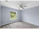A calm bedroom with grey wood-look tile flooring, a ceiling fan, and a bright window at 19185 Sherbrooke Ave, Port Charlotte, FL 33954