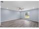 This bedroom features wood floors, blue walls, a ceiling fan, and a window overlooking the backyard at 19185 Sherbrooke Ave, Port Charlotte, FL 33954