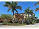 The clubhouse boasts Mediterranean-inspired architecture, framed by lush landscaping and towering palm trees under a clear blue sky at 1921 Monte Carlo Dr # 302, Sarasota, FL 34231