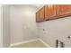 Functional laundry room equipped with overhead cabinets and utility connections, designed for efficient laundry tasks at 205 Sugarloaf Dr, Nokomis, FL 34275