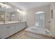 Bright bathroom featuring a double vanity, a large soaking tub, and neutral tile at 2148 Date Palm Way, Venice, FL 34292