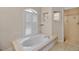 Elegant bathroom featuring a tiled tub, plantation shutters, and tile flooring at 2148 Date Palm Way, Venice, FL 34292