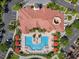 Aerial view showcases the pool and seating areas with umbrellas, lush landscaping, parking and terracotta roofs at 2741 Via Cipriani # 935A, Clearwater, FL 33764