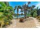 A tranquil backyard featuring a variety of lush palm trees, water view and stone pavers at 303 Cockle Shell Loop, Apollo Beach, FL 33572
