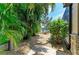 Lush, tropical backyard landscaping with stone walkway leading to lake and outdoor living space at 303 Cockle Shell Loop, Apollo Beach, FL 33572