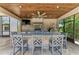 Outdoor kitchen with overhead fan, stone backsplash, stainless steel appliances, pizza oven, and bar stool seating at 303 Cockle Shell Loop, Apollo Beach, FL 33572