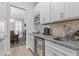 Elegant butler's pantry boasts white cabinetry, granite counters, wine cooler, and view into the dining area at 3344 Anchor Bay Trl, Bradenton, FL 34211