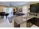 Open floor plan with granite countertops, black cabinets, stainless steel appliances, and a living area with grand piano at 3681 Divot Ln, Sarasota, FL 34232
