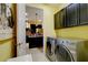 Laundry room featuring modern appliances and a view into the kitchen with dark cabinetry at 3681 Divot Ln, Sarasota, FL 34232
