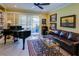 Sunlit living room with a piano, comfortable leather sofa, and access to the outdoor patio at 3681 Divot Ln, Sarasota, FL 34232