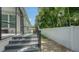 Relaxing back porch with steps leading to a well-maintained yard and a white fence, framed by lush greenery at 413 Partridge Cir, Sarasota, FL 34236