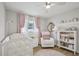 Cozy Bedroom features a white crib, chair, shelving, pink accents and decor throughout at 4344 Bent Tree Blvd, Sarasota, FL 34241