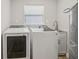 Bright laundry room with newer washer and dryer, utility sink, and cabinet storage at 4344 Bent Tree Blvd, Sarasota, FL 34241