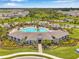 Aerial view of community clubhouse, pool, palm trees, manicured landscaping, and surrounding homes at 4405 Weathered Moss Gln, Palmetto, FL 34221