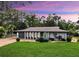 Charming single-story home with lush lawn, decorative sign, blue door, and a backdrop of mature trees at 4455 Emerald Ridge Dr, Sarasota, FL 34233