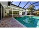 Inviting screened-in pool area with a brick patio and lush tropical landscaping at 483 Partridge Cir, Sarasota, FL 34236
