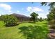 Lush green backyard features a home with a screened lanai and mature trees at 5121 Serata Dr, Lakewood Ranch, FL 34211
