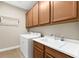 Laundry room with a utility sink, wooden cabinets, and modern washer and dryer at 5121 Serata Dr, Lakewood Ranch, FL 34211