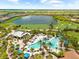 Aerial shot of a large pool area surrounded by palm trees, lounge chairs, and a serene lake view at 5121 Serata Dr, Lakewood Ranch, FL 34211