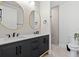Modern bathroom features a double vanity with matte black fixtures, grey cabinets, and oval mirrors with gold trim at 5339 Gulfport Ter, Port Charlotte, FL 33981