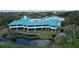 Aerial view of a commercial building with turquoise roofing overlooking pond and greenery at 5839 Los Verdes Ct, Bradenton, FL 34210