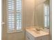 Bright bathroom features a sink with a large mirror and window with plantation shutters at 5839 Los Verdes Ct, Bradenton, FL 34210