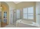Bright bathroom featuring a glass shower, tub, and window with plantation shutters at 5839 Los Verdes Ct, Bradenton, FL 34210