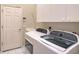A laundry room features a washer, dryer, utility sink, cabinets, and a door to the exterior at 5839 Los Verdes Ct, Bradenton, FL 34210