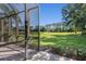 View of the lush backyard and pond from a screened in patio, complete with view of a golf green at 7419 Birds Eye Ter, Bradenton, FL 34203