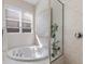 Bright bathroom with tile flooring, a soaking tub, and a glass enclosed shower by a window with blinds at 7419 Birds Eye Ter, Bradenton, FL 34203