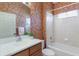 Small bathroom with wallpaper, a single sink vanity and a shower over tub combination with tile surround at 7419 Birds Eye Ter, Bradenton, FL 34203