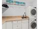 This convenient laundry room boasts white cabinets, a sink, and stacked washer/dryer units at 760 Azure Rd, Venice, FL 34293