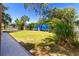 Lush backyard featuring green grass, mature trees, and sidewalk access at 760 Azure Rd, Venice, FL 34293