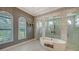 Elegant bathroom featuring a soaking tub, glass shower, marble floors and three arched windows at 7665 Haddington Cv, Bradenton, FL 34202