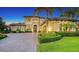 Elegant two-story home featuring a beautiful front yard with manicured landscaping, palm trees and a large paver driveway at 7665 Haddington Cv, Bradenton, FL 34202