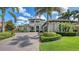 Elegant two-story home featuring a beautiful front yard with manicured landscaping, palm trees and a large paver driveway at 7665 Haddington Cv, Bradenton, FL 34202