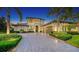 Elegant two-story home featuring a beautiful front yard with manicured landscaping, palm trees and a large paver driveway at 7665 Haddington Cv, Bradenton, FL 34202