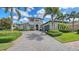 Landscaped front exterior featuring a circular driveway, lush greenery, and a stately two-story home at 7665 Haddington Cv, Bradenton, FL 34202