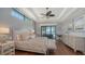 Bright main bedroom featuring tray ceilings, wood floors, a ceiling fan, and private balcony access at 7665 Haddington Cv, Bradenton, FL 34202