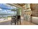 Outdoor kitchen with stainless steel appliances and seating, overlooking the pool and a scenic lake view at 7665 Haddington Cv, Bradenton, FL 34202
