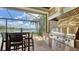 View of an outdoor kitchen featuring modern appliances, seating, and a picturesque backdrop of the lake at 7665 Haddington Cv, Bradenton, FL 34202