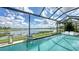 A screened-in pool with lake views features sleek lounge chairs and manicured landscaping at 7665 Haddington Cv, Bradenton, FL 34202