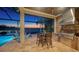 Covered outdoor kitchen and dining area overlooking the pool and tranquil lake, perfect for outdoor entertaining and relaxation at 7665 Haddington Cv, Lakewood Ranch, FL 34202