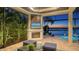 Inviting outdoor living space with a fireplace, comfortable seating, and a tranquil lake view, perfect for relaxation and entertaining at 7665 Haddington Cv, Lakewood Ranch, FL 34202