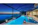 Gorgeous screened-in pool area with a spa, fire bowls, and ambient lighting, perfect for enjoying the calming lake view at 7665 Haddington Cv, Lakewood Ranch, FL 34202