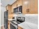 Modern kitchen featuring stainless appliances, white countertops, and light wood cabinets at 800 S Blvd Of The Presidents # 16, Sarasota, FL 34236