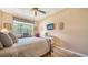 Comfortable bedroom featuring a ceiling fan and a window overlooking the lush greenery outside at 8183 Nice Way, Sarasota, FL 34238