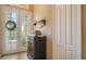 Elegant foyer with a decorative cabinet, double doors and natural light at 8183 Nice Way, Sarasota, FL 34238
